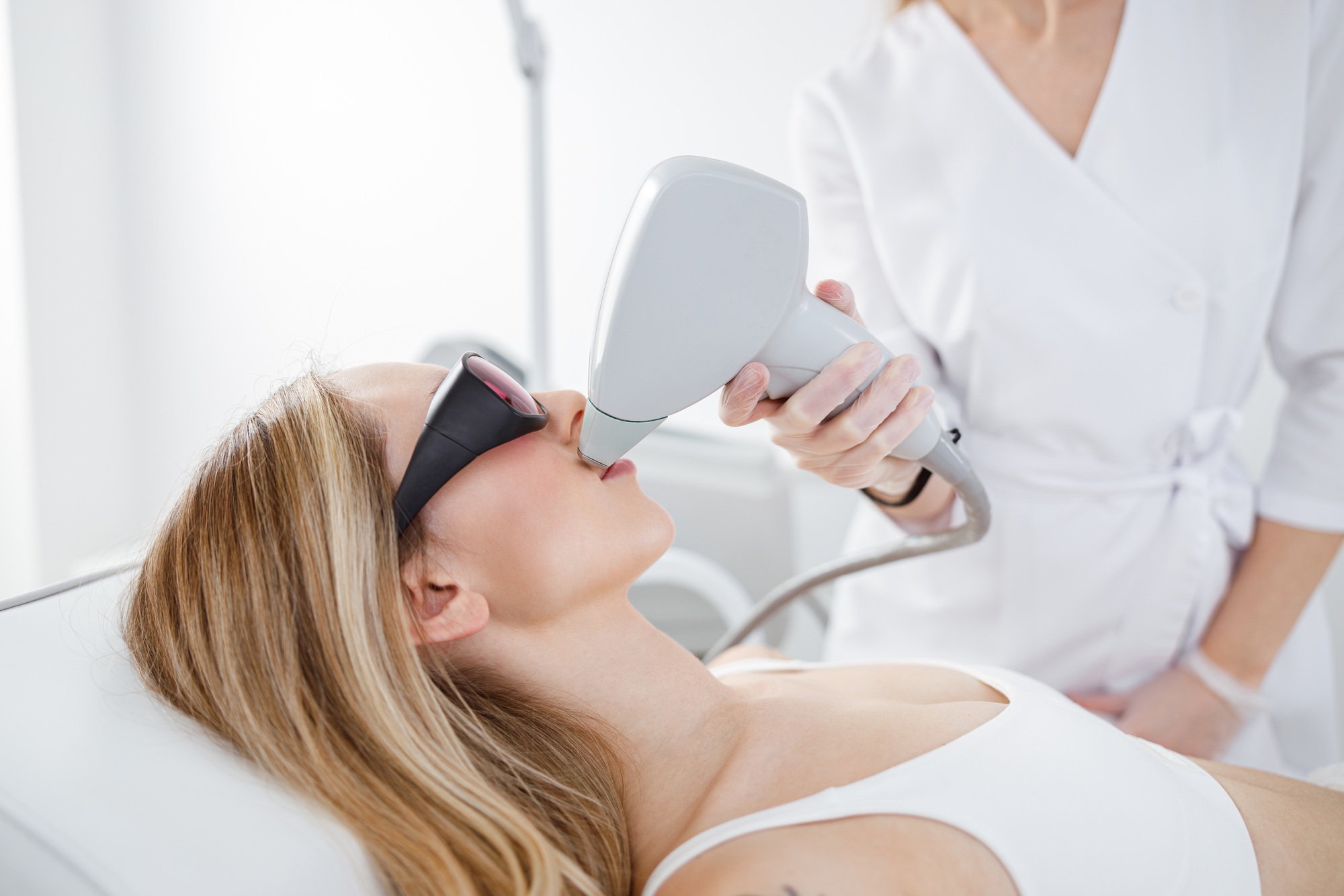 Woman receiving facial laser hair removal treatment in beauty salon